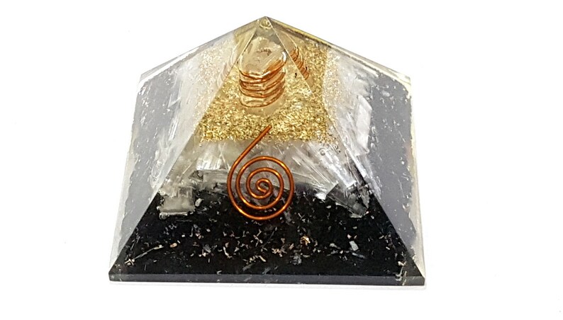 May include: A black, white, and gold layered crystal pyramid with a copper wire spiral on top. The pyramid is made of selenite, clear quartz, and black tourmaline.