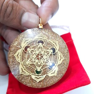 May include: Gold-toned pendant with a geometric design and colorful stones. The pendant is on a red velvet pouch.