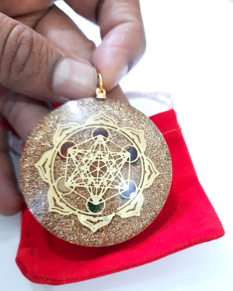 May include: Gold-toned pendant with a geometric design and colorful stones. The pendant is on a red velvet pouch.
