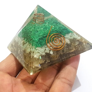 May include: Green, white, and brown crystal pyramid with a copper wire spiral design. The pyramid is made of various crystals and is a decorative object.
