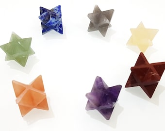 Può includere: Sette punte di cristallo a forma di stella di vari colori, tra cui verde, blu, grigio, giallo, arancione, rosso e viola. I cristalli sono disposti in un cerchio su uno sfondo bianco.