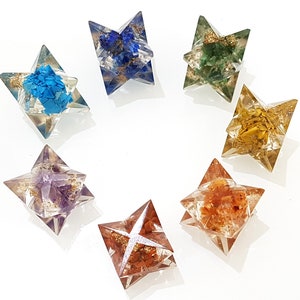 May include: Seven clear star-shaped crystal ornaments with different colored crystals inside. The crystals are blue, green, yellow, purple, and orange.