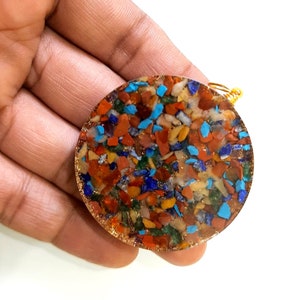 May include: A round, multi-colored, crystal pendant with a gold wire loop. The pendant is made of many small, colorful stones, including red, orange, yellow, green, blue, and purple.