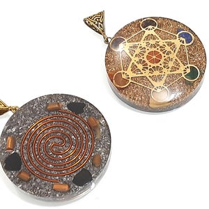 Pu&ograve; includere: Due ciondoli rotondi con anelli di metallo dorati. Il ciondolo a sinistra ha uno sfondo argentato con un design a spirale color rame e pietre nere. Il ciondolo a destra ha uno sfondo marrone con un design geometrico dorato e pietre colorate.