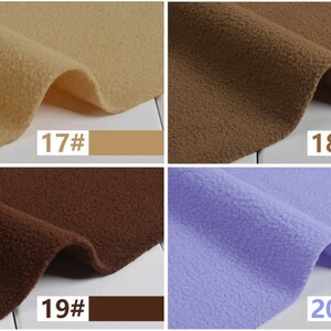 May include: Close-up of four swatches of fleece fabric in various colors. The colors include tan, brown, dark brown, and lavender. Each swatch has a corresponding color label with a number. The fabric has a soft, textured appearance.