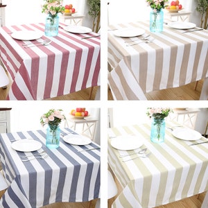 Puede incluir: Cuatro manteles a rayas en diferentes colores: rosa y blanco, beige y blanco, gris y blanco y verde claro y blanco. Cada mantel está colocado sobre una mesa cuadrada con dos platos blancos, dos tenedores y dos cucharas en cada mesa.