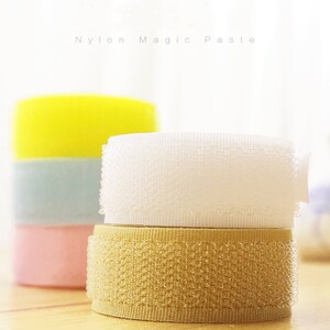 May include: Three rolls of nylon magic tape, one white, one beige, and one yellow. The tape is a hook and loop fastener.