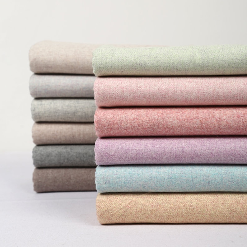 May include: A stack of fabric swatches in various colours, including beige, light green, pink, purple, blue, and peach. The fabric has a textured, slightly fuzzy appearance.
