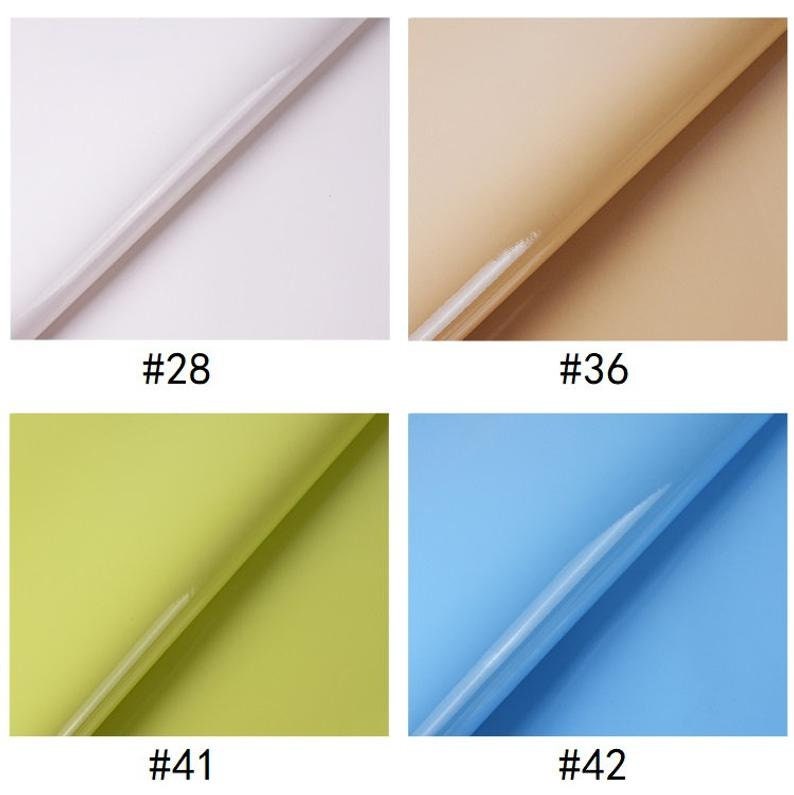 Puede incluir: Cuatro muestras de papel de regalo, cada una doblada por la mitad para mostrar el color y la textura. Los colores son blanco, beige, verde claro y azul claro.