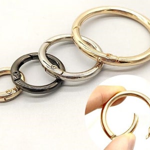 Può includere: Quattro portachiavi in metallo di diverse dimensioni con chiusura girevole. I portachiavi sono dorati, argentati e neri.