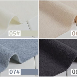 May include: Four samples of fleece fabric in different colors: off-white, beige, light blue, and dark gray. Each sample is labeled with a number and a corresponding color swatch. The fabric has a soft, textured appearance.