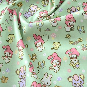 K&ouml;nnte beinhalten: Gr&uuml;ner Stoff mit einem sich wiederholenden Muster aus rosa und wei&szlig;en Comicfiguren, Pilzen und anderen kleinen Details. Die Figuren tragen rosa Schleifen und haben gro&szlig;e Augen.