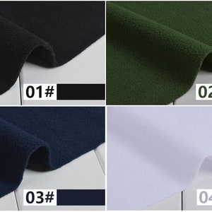 May include: A fabric sample with four color swatches: black, dark green, navy blue, and white. Each swatch is labeled with a number and color name. The fabric appears to be a soft, textured material.
