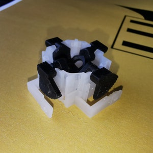 Peut inclure: Un connecteur en plastique blanc avec quatre leviers noirs. Le connecteur est de forme carrée et est conçu pour relier deux meubles.