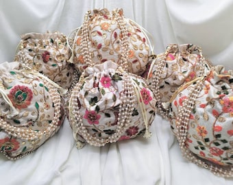 May include: Five white drawstring bags with floral embroidery and pearl trim. The bags are arranged in a circle on a white fabric background.