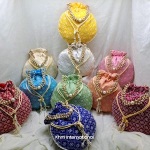 May include: Assortment of colorful drawstring bags with pearl embellishments and intricate patterns. The bags are made of fabric and have a traditional Indian design.