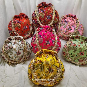 May include: Seven colourful drawstring bags with floral embroidery and pearl embellishments. The bags are made of fabric and have a round shape.
