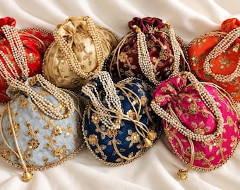Könnte beinhalten: Eine Sammlung von sieben Beuteltaschen mit Kordelzug in Rot, Gold, Burgunder, Orange, Hellblau, Dunkelblau und Fuchsia. Jede Tasche ist mit goldener Blumenstickerei, Pailletten und einem Perlenhenkel mit goldenem Metallverschluss versehen.