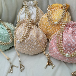 Set of multiple handmade embroidered potli bags arranged beautifully, perfect for bulk wedding favors, return gifts and party giveaways. Ideal for Indian weddings, baby showers and festive gifting. Uniform design, premium quality fabric and elegant finish make it a perfect bulk purchase option.