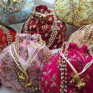 Colorful silk potli bags with heavy gold zari embroidery and pearl handle detailing, handcrafted Indian drawstring pouch for women, luxury ethnic handbags suitable for bridal wear, wedding parties, festive gifting, diwali celebrations, unique return gift ideas, elegant traditional purse for saree and lehenga outfits, bohemian style accessory popular among USA buyers for handmade and artisan fashion products
