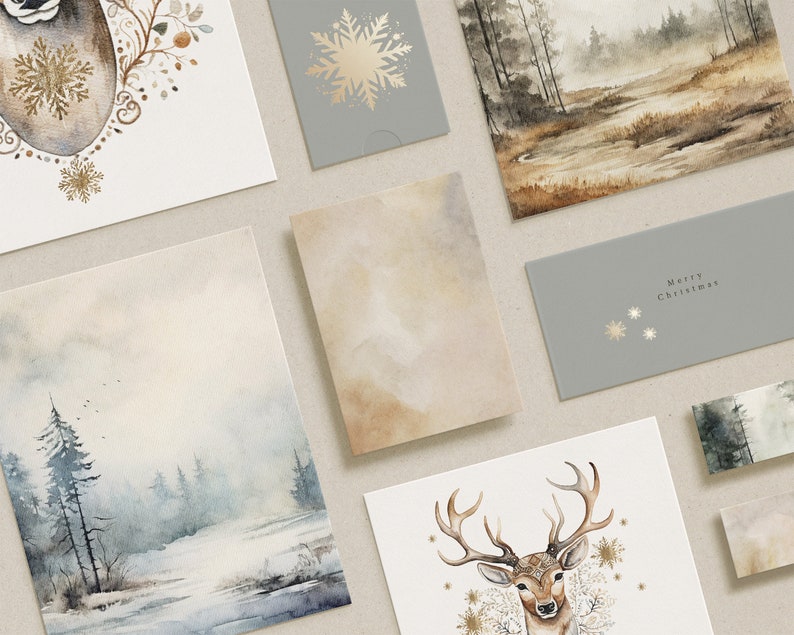 May include: A selection of watercolour Christmas cards and envelopes. The cards display winter scenes, a deer, and snowflake designs in gold and neutral tones. One envelope reads "Merry Christmas".