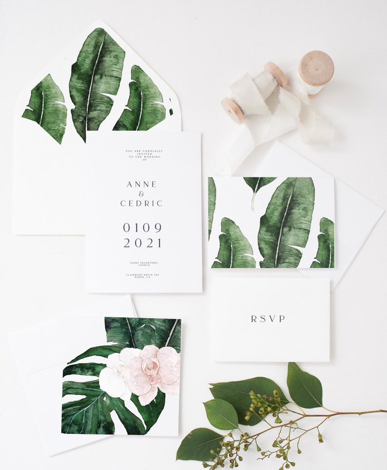 May include: Wedding invitation suite with a tropical theme. The invitation features a watercolor illustration of banana leaves and the text "Anne & Cedric 01.09.2021". The RSVP card features a simple "RSVP" in a minimalist font.