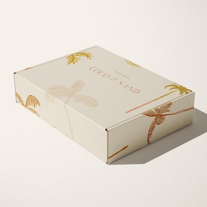 May include: A beige cardboard box with a palm tree design and the text "Coco & Sand" printed on the top.