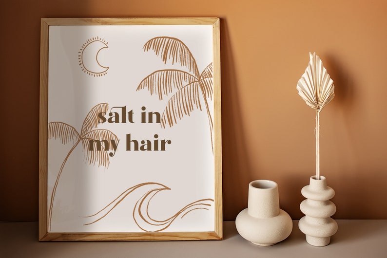 May include: A framed print with a white background and brown line drawings of palm trees, waves, and a crescent moon. The text "salt in my hair" is written in brown letters.