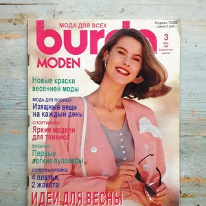 May include: A magazine cover featuring a woman with long brown hair wearing a pink jacket and sunglasses. The magazine is titled "Burda MODEN" and has the text "New colours of spring fashion" and "Ideas for spring" on the cover.