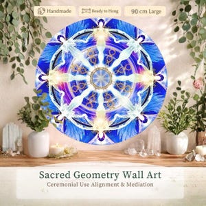 May include: A round wall art piece with a blue and white geometric design, featuring angel-like figures. The artwork is 35 inches in diameter and is labeled "Sacred Geometry Wall Art." It is described as handmade and ready to hang.