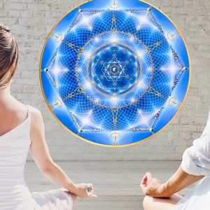 Puede incluir: Un gran diseño de mandala redondo azul y dorado con intrincados patrones geométricos. El mandala es el punto focal, con un diseño simétrico detallado. La imagen muestra a dos personas meditando frente al mandala.