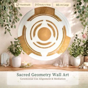 Op de afbeelding: Een groot, handgemaakt Sacred Geometry wandkunstwerk in wit en goud, 66 cm in diameter. Het ontwerp toont concentrische cirkels en geometrische vormen. De tekst "Sacred Geometry Wall Art" en "Ceremonial Use Alignment & Mediation" is zichtbaar.