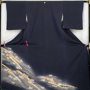 May include: A dark navy blue kimono with a decorative pattern of gold and white bamboo and waves. The kimono is displayed in a black frame. The bottom of the kimono has a gradient effect.