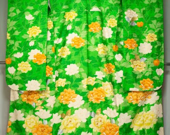 May include: A vibrant green kimono with a floral pattern featuring yellow, orange, and white flowers. The fabric is adorned with a repeating design of leaves and blossoms, creating a lively and colorful aesthetic. The text "着物夢屋 | kimono-yumeya.com | Kimono Dream Shop" is visible.