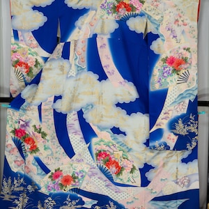 May include: A vibrant blue kimono with a cloud and floral design. The kimono features white clouds, pink and purple accents, and colorful floral arrangements. The design includes fans and a landscape at the bottom.