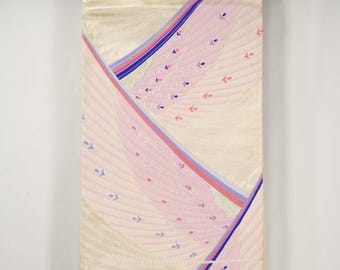 May include: A cream-colored kimono with a pink and blue feather-like design. The fabric has a subtle sheen, with the design featuring curved lines and small, stylized floral accents. The kimono is hanging from a black rod.