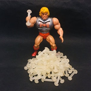 May include: A large pile of clear plastic doll eyes, with a plastic action figure standing in front of the pile. The action figure is holding a clear plastic rod.