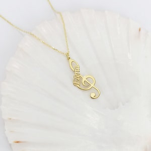May include: Gold necklace with a treble clef pendant that has the name "Elena" inscribed on it.