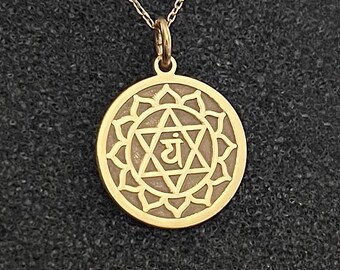May include: Gold pendant necklace featuring the Anahata chakra symbol, a stylized heart with the Sanskrit word "YAH" in the center, surrounded by a lotus flower design.