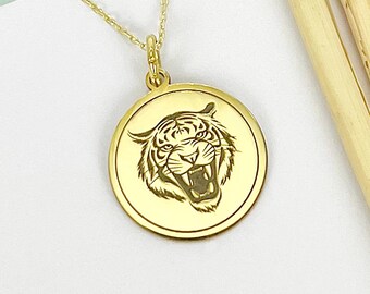 May include: A gold necklace with a round pendant featuring a detailed engraved image of a tiger's face.
