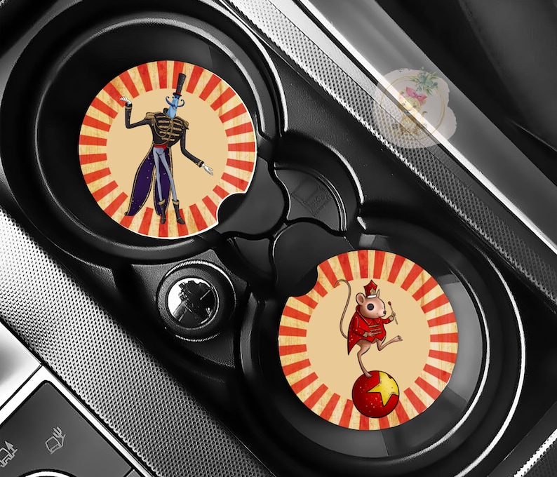 Pu&ograve; includere: Due sottobicchieri per auto con disegni a tema circo. Uno presenta un presentatore dal volto blu con cappotto nero e cilindro, l'altro un topo con un cappotto rosso in equilibrio su una palla rossa. Entrambi hanno uno sfondo color crema con strisce rosse e crema.