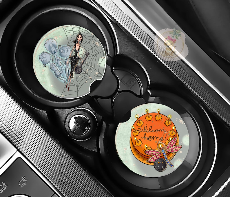 Pu&ograve; includere: Due sottobicchieri per auto con design unici. Uno presenta una donna in abito nero su una ragnatela con fantasmi. L'altro ha una torta arancione con candele accese e una libellula, con la scritta "welcome home!"