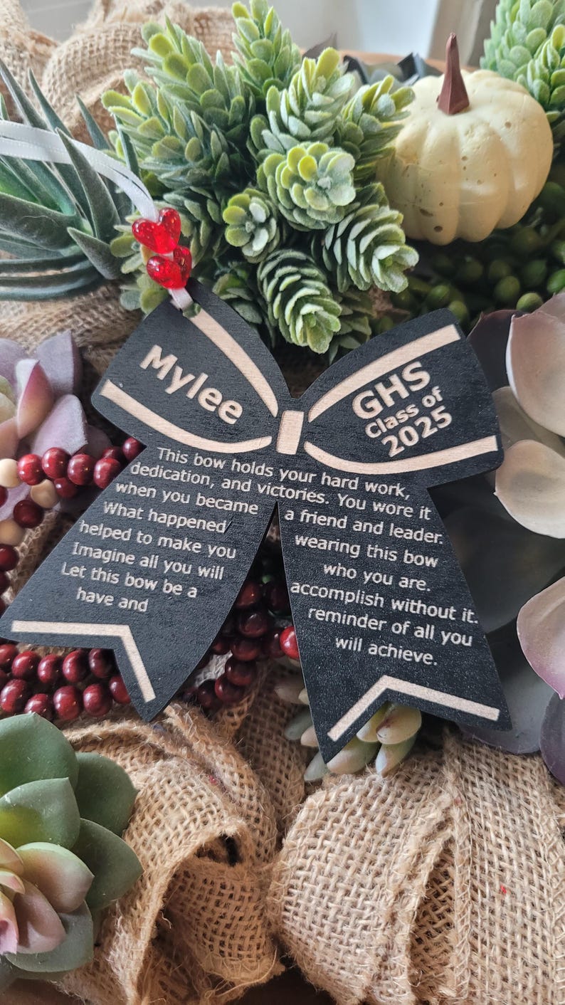 May include: A black wooden bow with the name "Mylee" and the text "GHS Class of 2025" on it. The bow has a message about hard work, dedication, and victories.