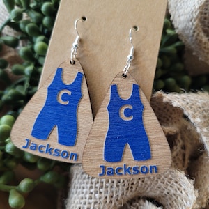 May include: A pair of wooden earrings shaped like wrestling singlets. The singlets are blue with a white "C" on the front. The earrings are personalized with the name "Jackson".