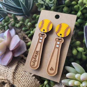Puede incluir: Un par de pendientes colgantes con un dije de s&oacute;ftbol amarillo unido a un dije de bate de b&eacute;isbol de madera clara. Un bate est&aacute; grabado con el nombre Waylyn y el otro bate est&aacute; grabado con el n&uacute;mero 4. Los pendientes se presentan en una tarjeta.