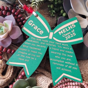 May include: Green wooden bow with the text "Grace" and "MELHS Class of 2025" on it. The bow has a message about hard work, dedication, and victories.