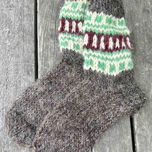 May include: A pair of brown wool socks with a green and white geometric pattern at the top. The socks are knitted and have a fuzzy texture.