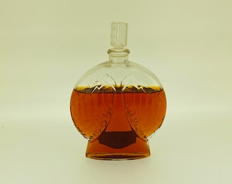 May include: A clear glass bottle with a textured surface and a stopper. The bottle is filled with a dark amber liquid.