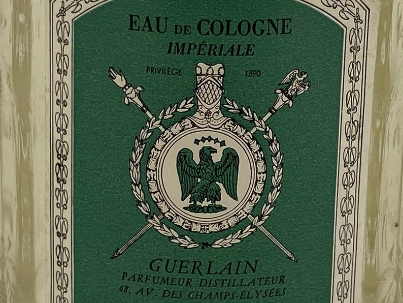 May include: A green and white label with the text "EAU DE COLOGNE IMPERIALE" and "GUERLAIN PARFUMEUR DISTILLATEUR 68. AV. DES CHAMPS-ELYSEES". The label features a crest with a bird and a laurel wreath.