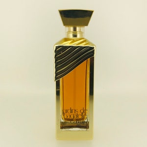 May include: A gold bottle of perfume with a gold cap and a label that reads "Jardins de Bagatelle Guerlain Paris".